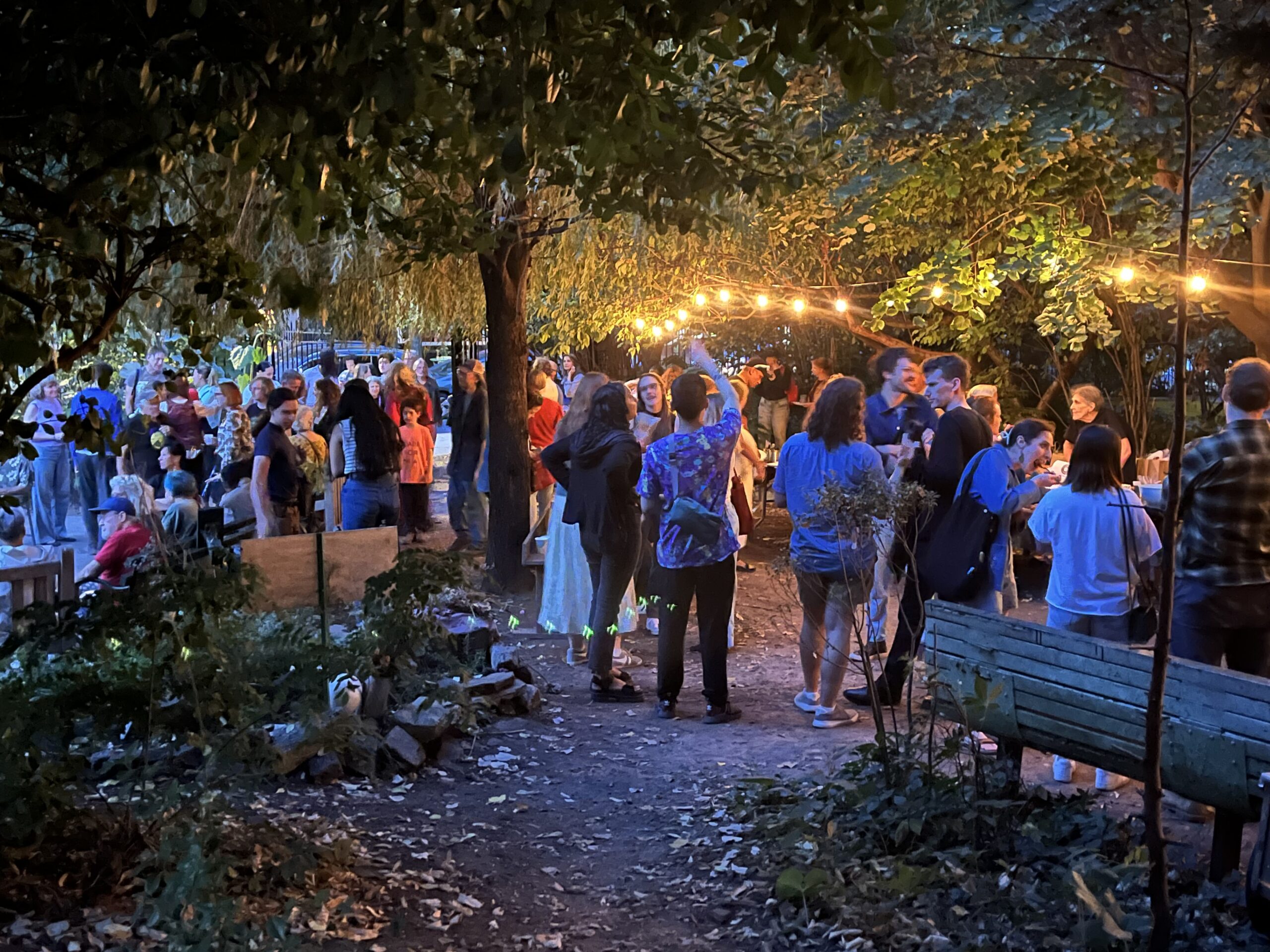 A crowd of neighbors filling Green Oasis garden for an evening performance at a past Harvest Arts Festival.